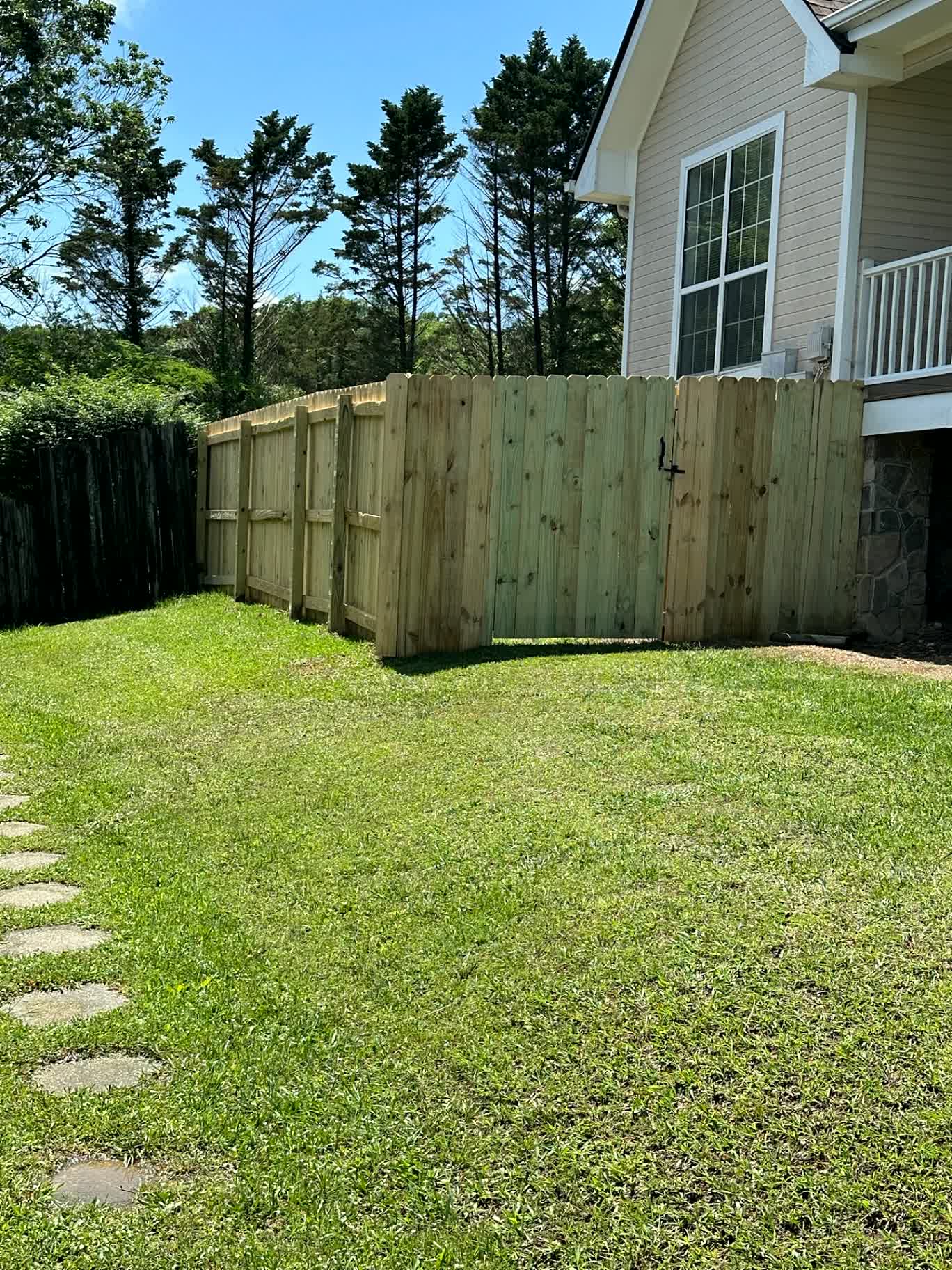 Wood privacy fence with a gate meeting the house on a lawn