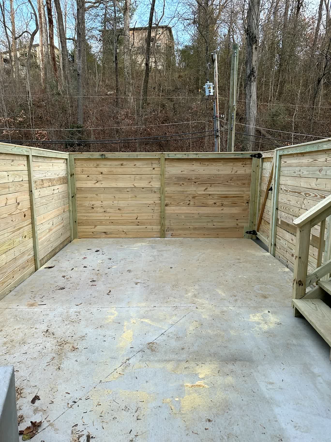 Horizontal wood enclosure around a concrete patio with a walk gate