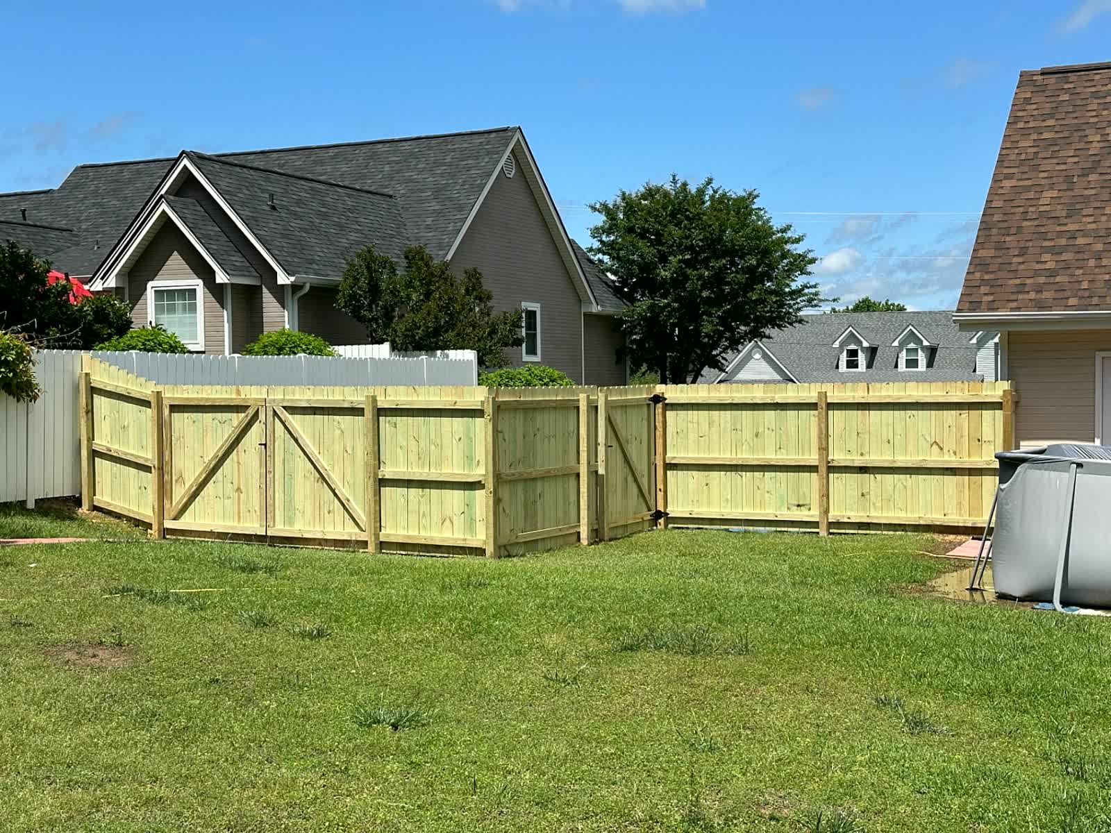 Wood dog-ear fence with double gates enclosing a backyard