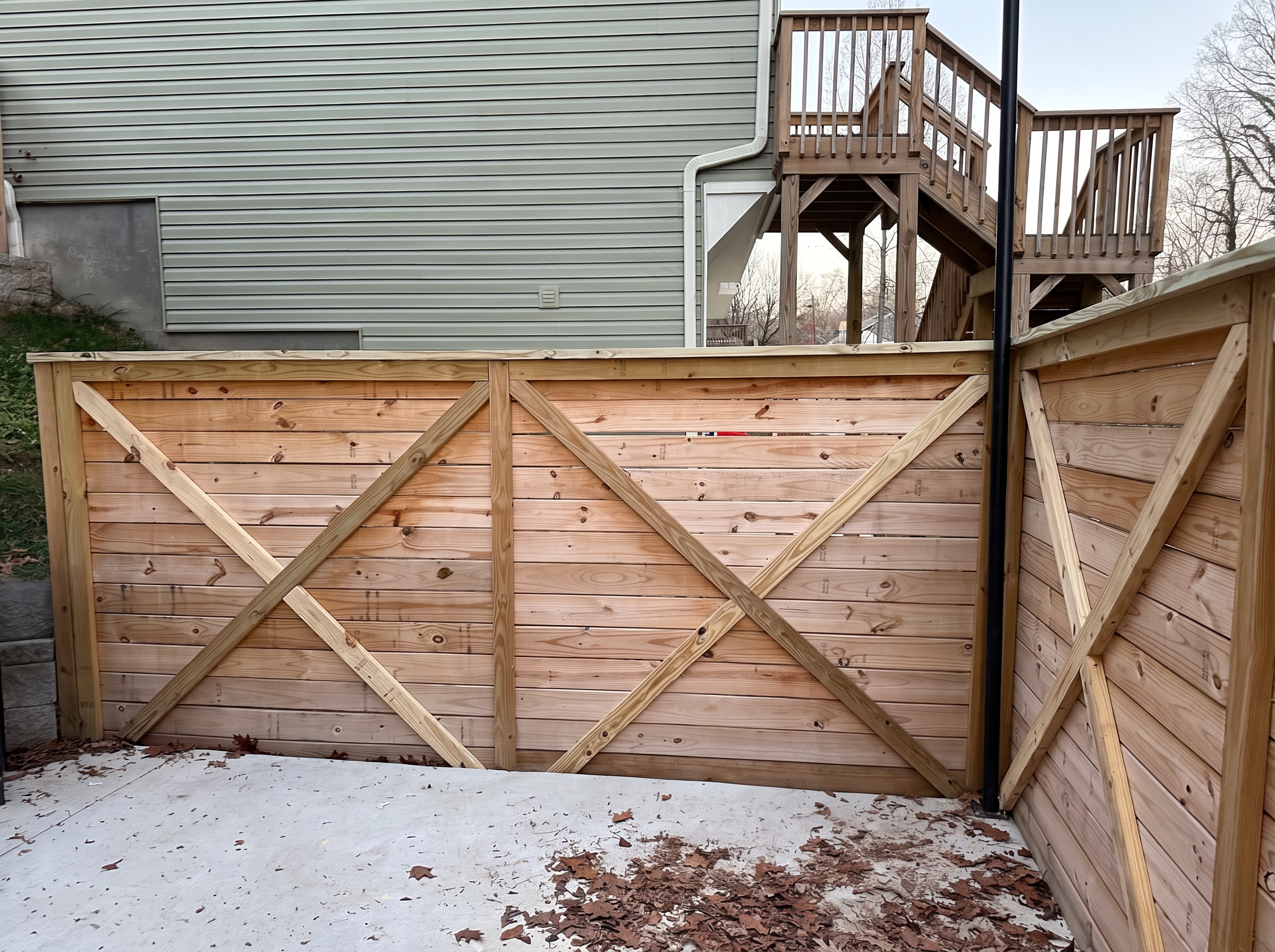 Horizontal wood enclosure with X bracing beside a raised deck