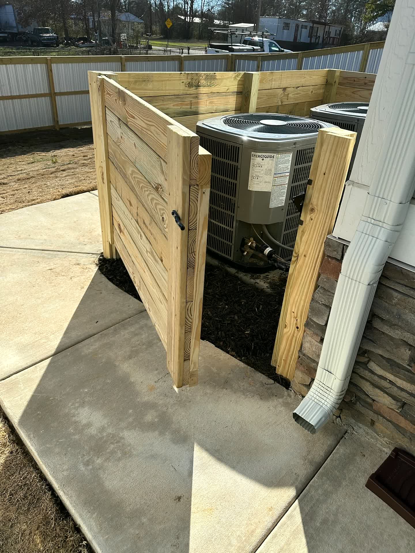 Wood slat gates screening air conditioning units at a home