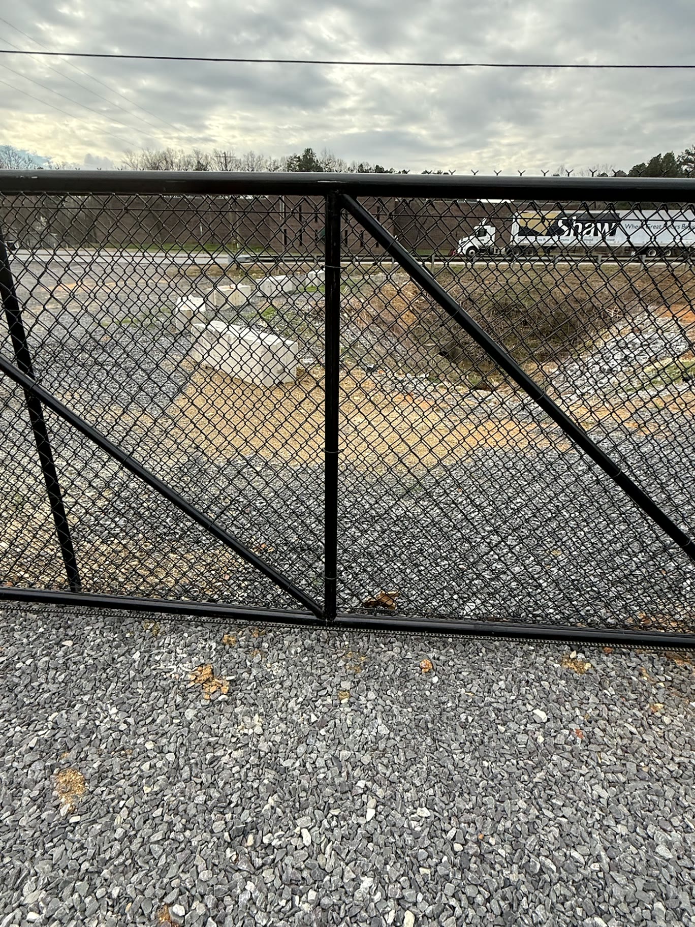 Close-up of a black chain-link cantilever gate frame on a gravel yard