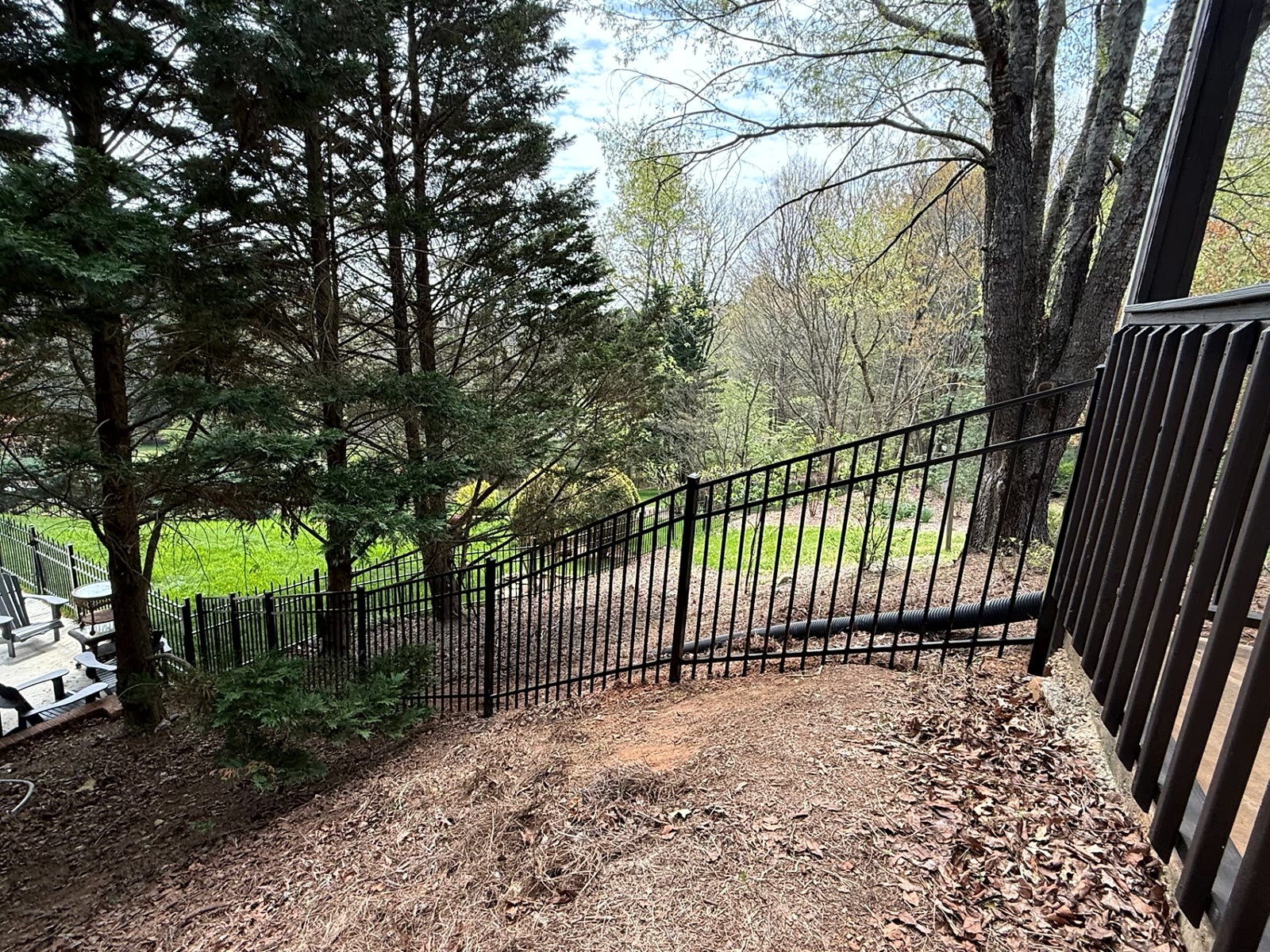 Raked aluminum fence panels following a steep wooded slope