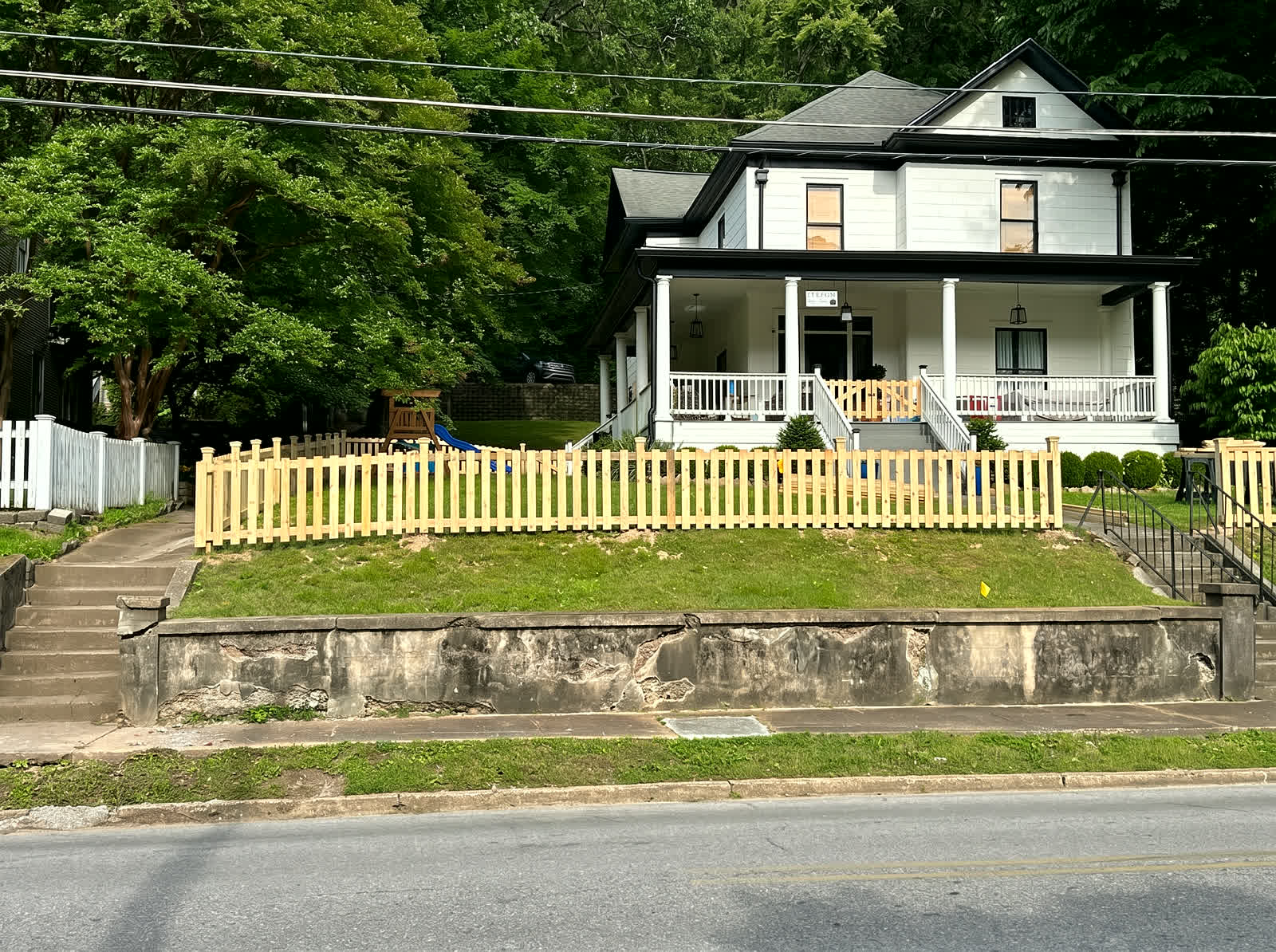 Scalloped wood picket fence around a historic home's front yard