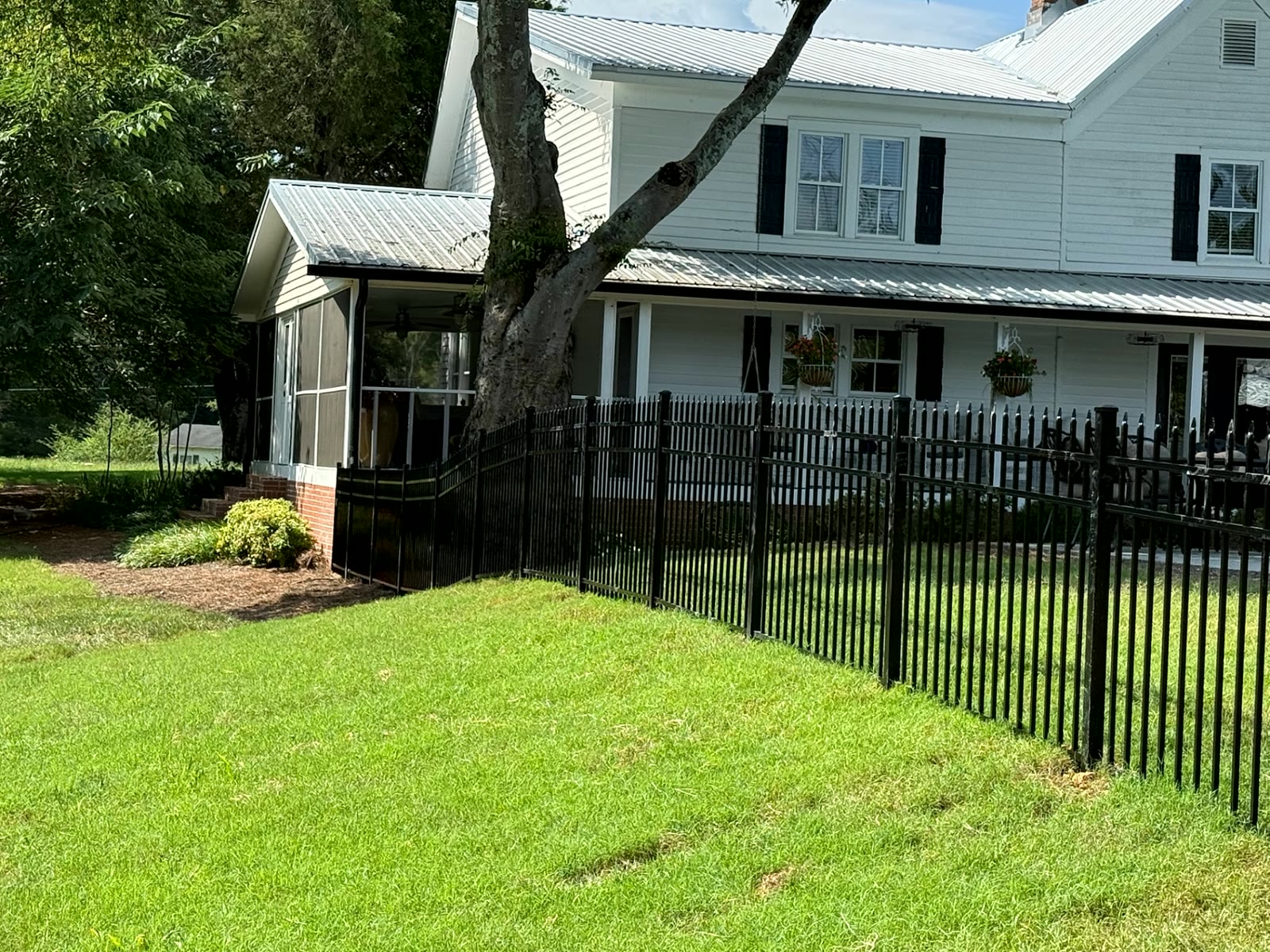 Black ornamental fence around a white farmhouse lawn