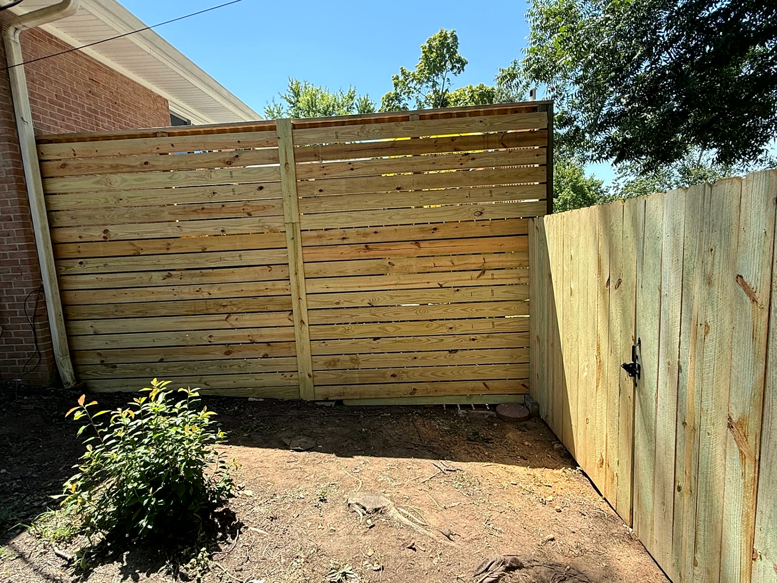 Horizontal slat wood privacy screen beside a brick home