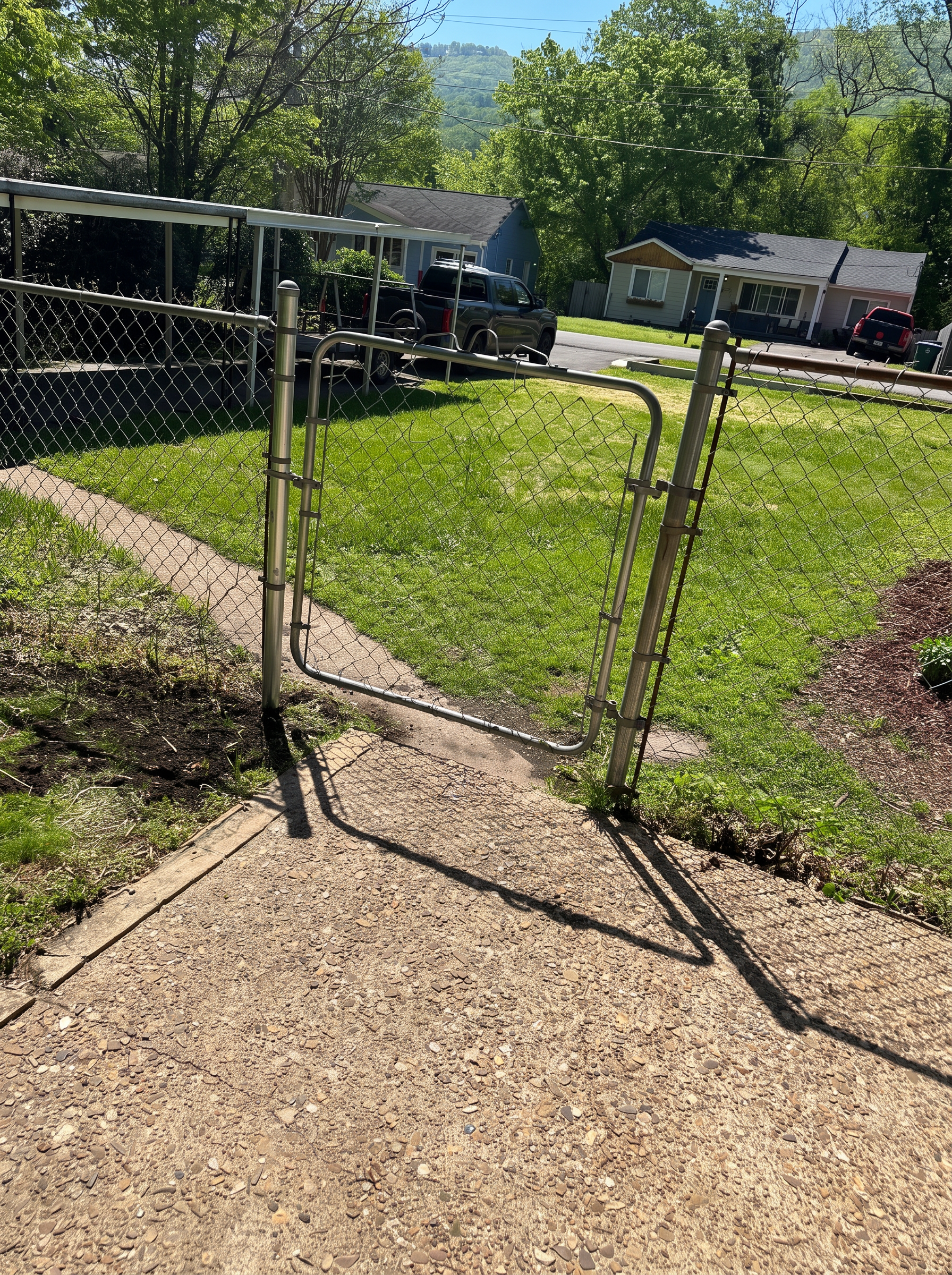 Galvanized chain-link walk gate across a concrete residential walkway