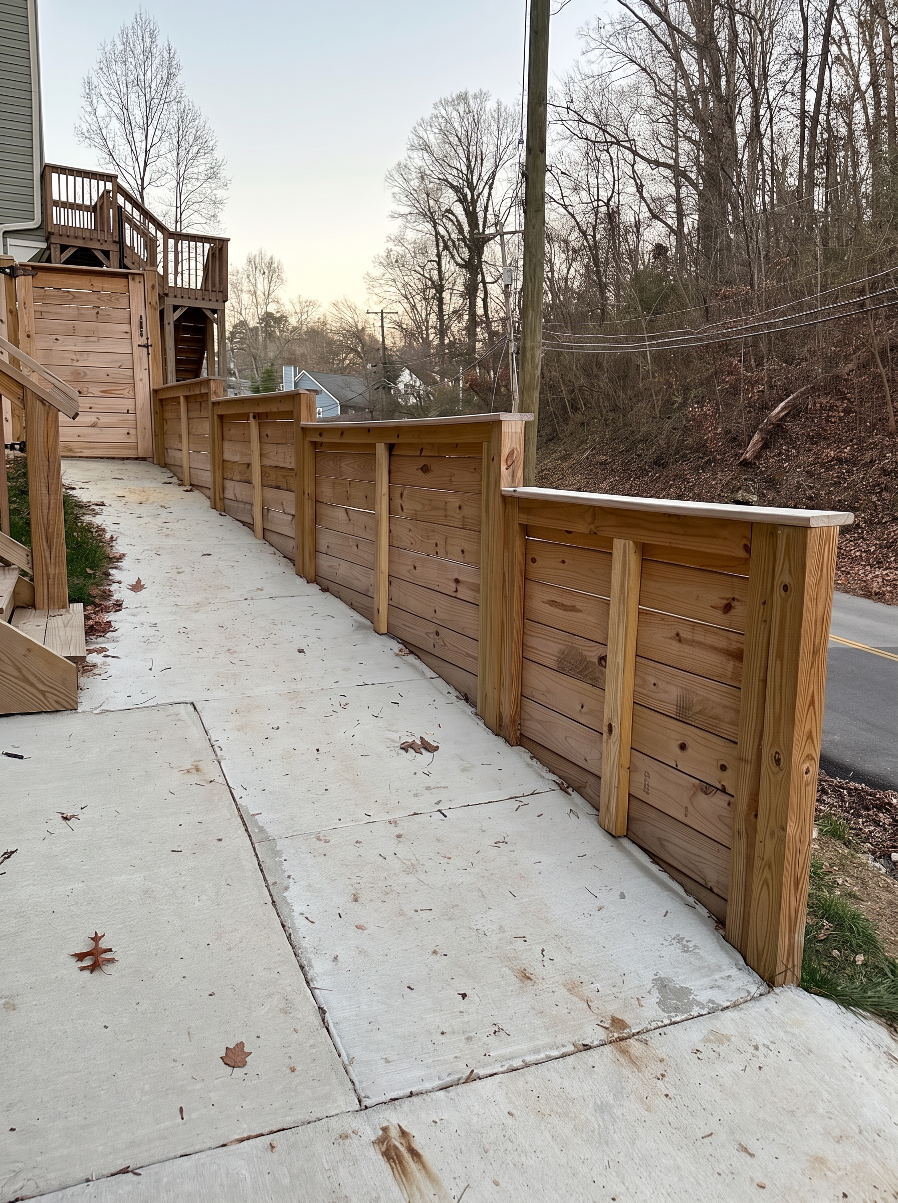 Capped horizontal wood fence stepping down beside a concrete walkway