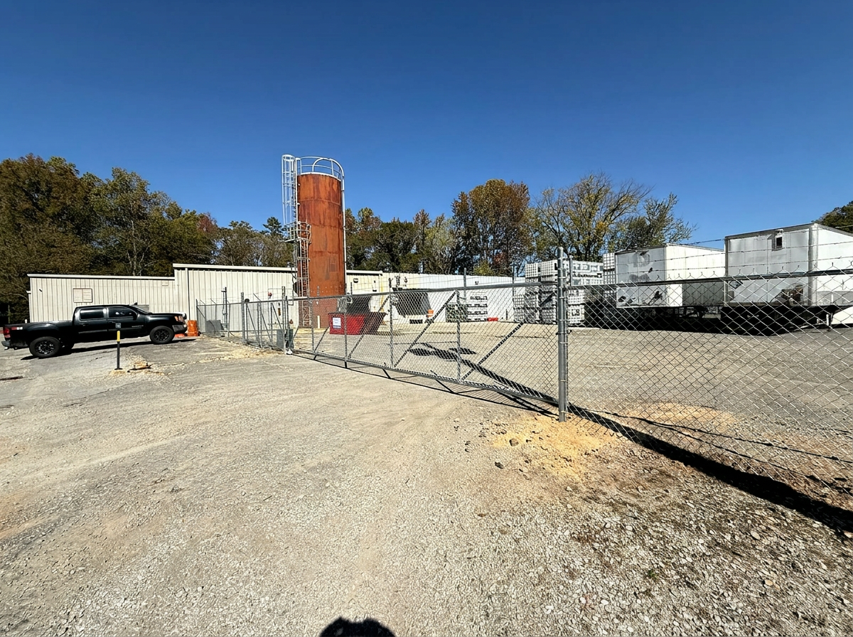 Long galvanized chain-link security fence and slide gate at an industrial yard