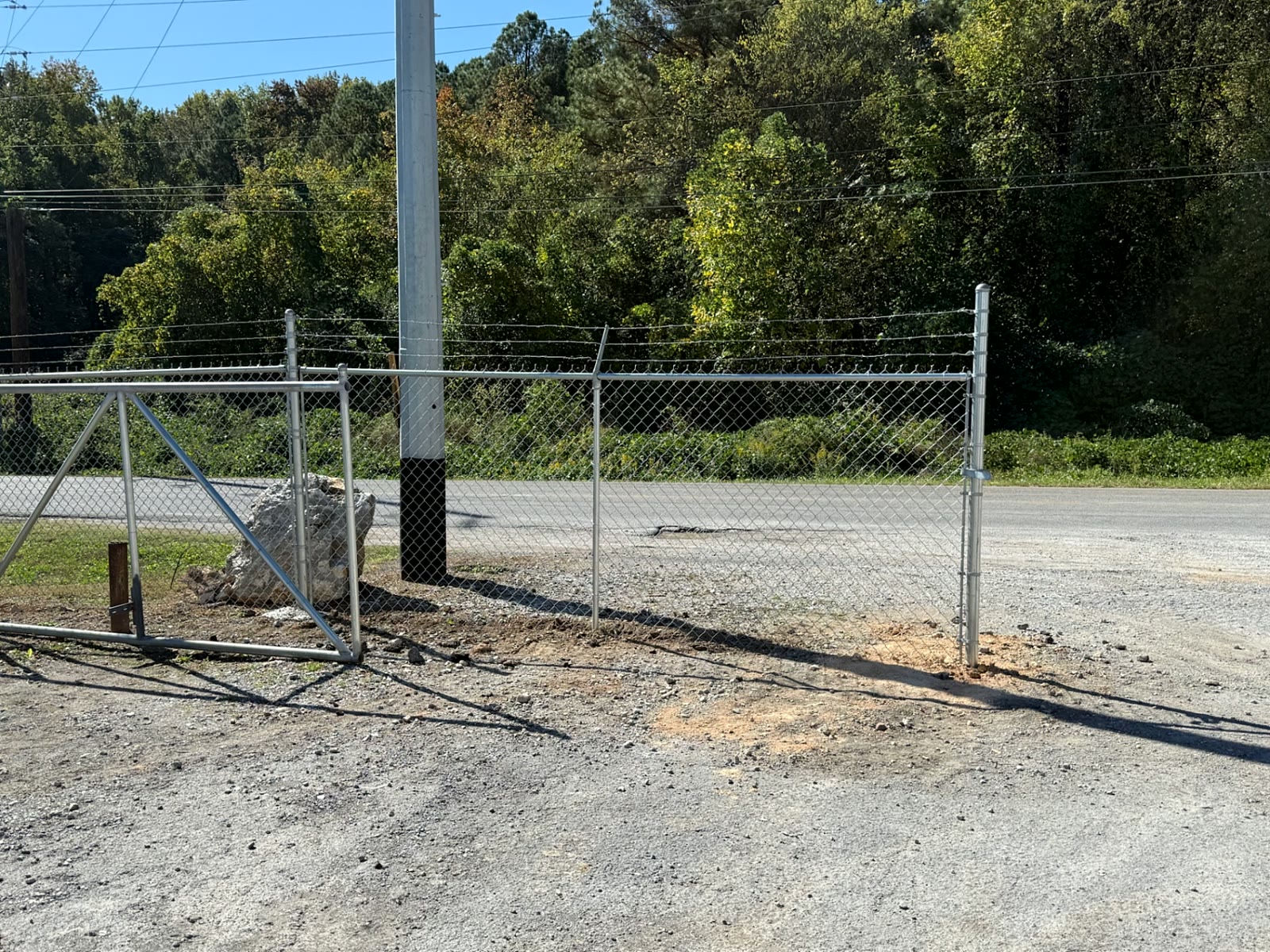 Galvanized chain-link fence with barbed-wire top beside a cantilever gate