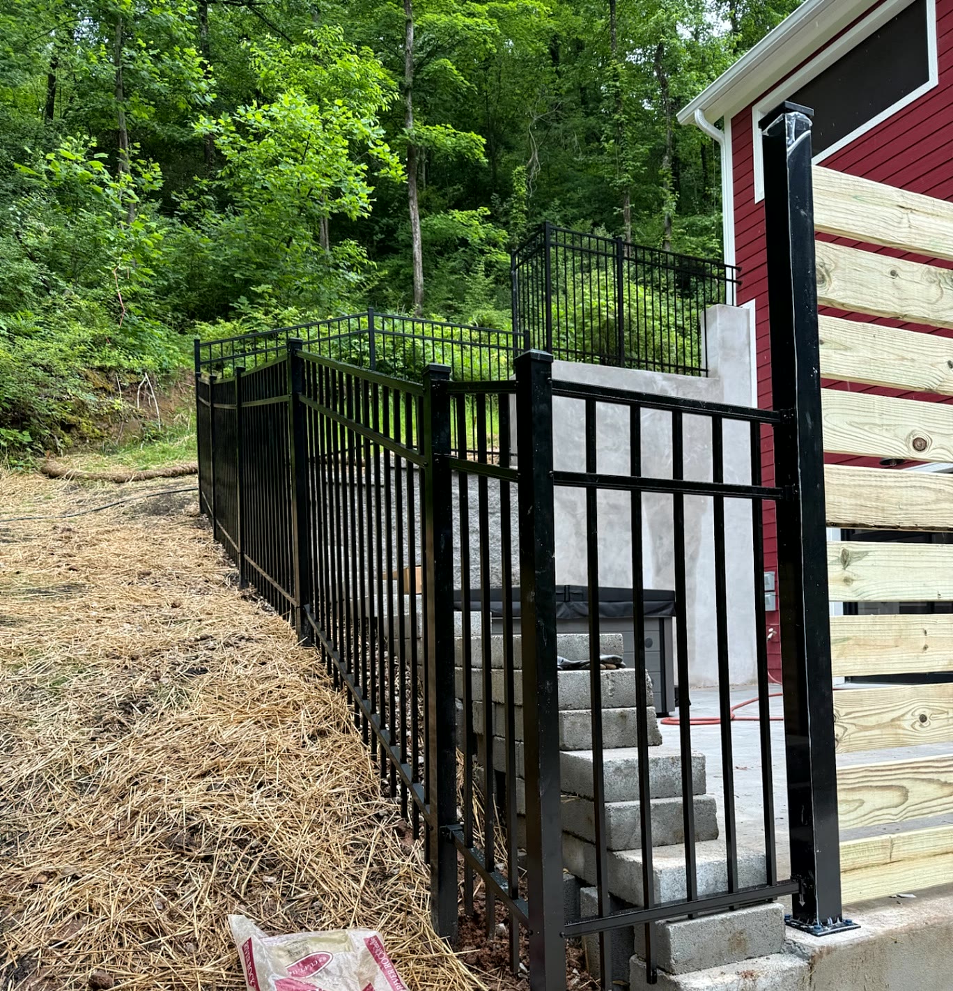 Aluminum fence stepping along a block retaining wall