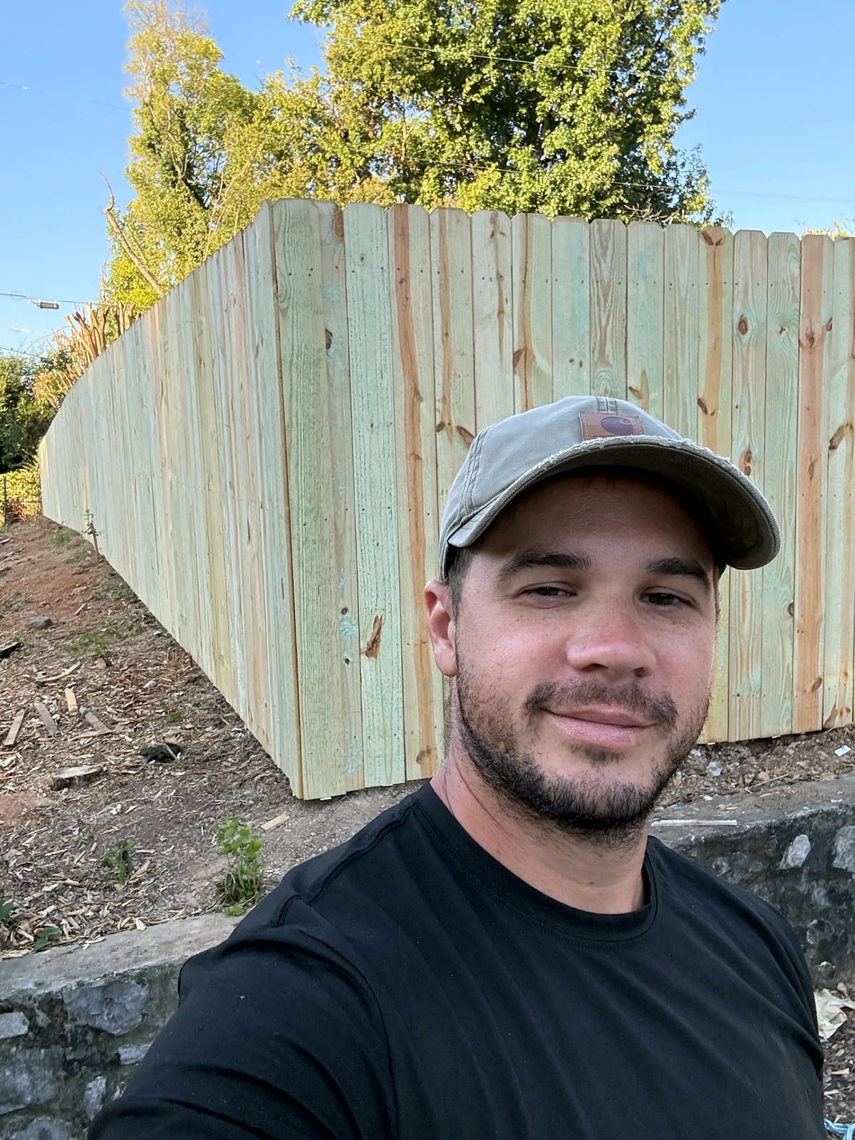 Logan Walker, owner of Environmental Barriers, in front of a freshly built wood privacy fence