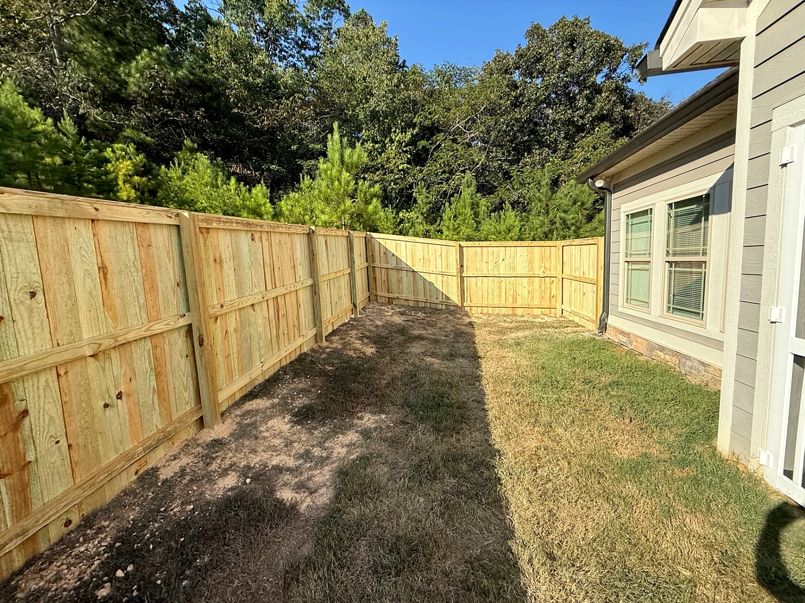Wood privacy fence with posts and rails enclosing a side yard