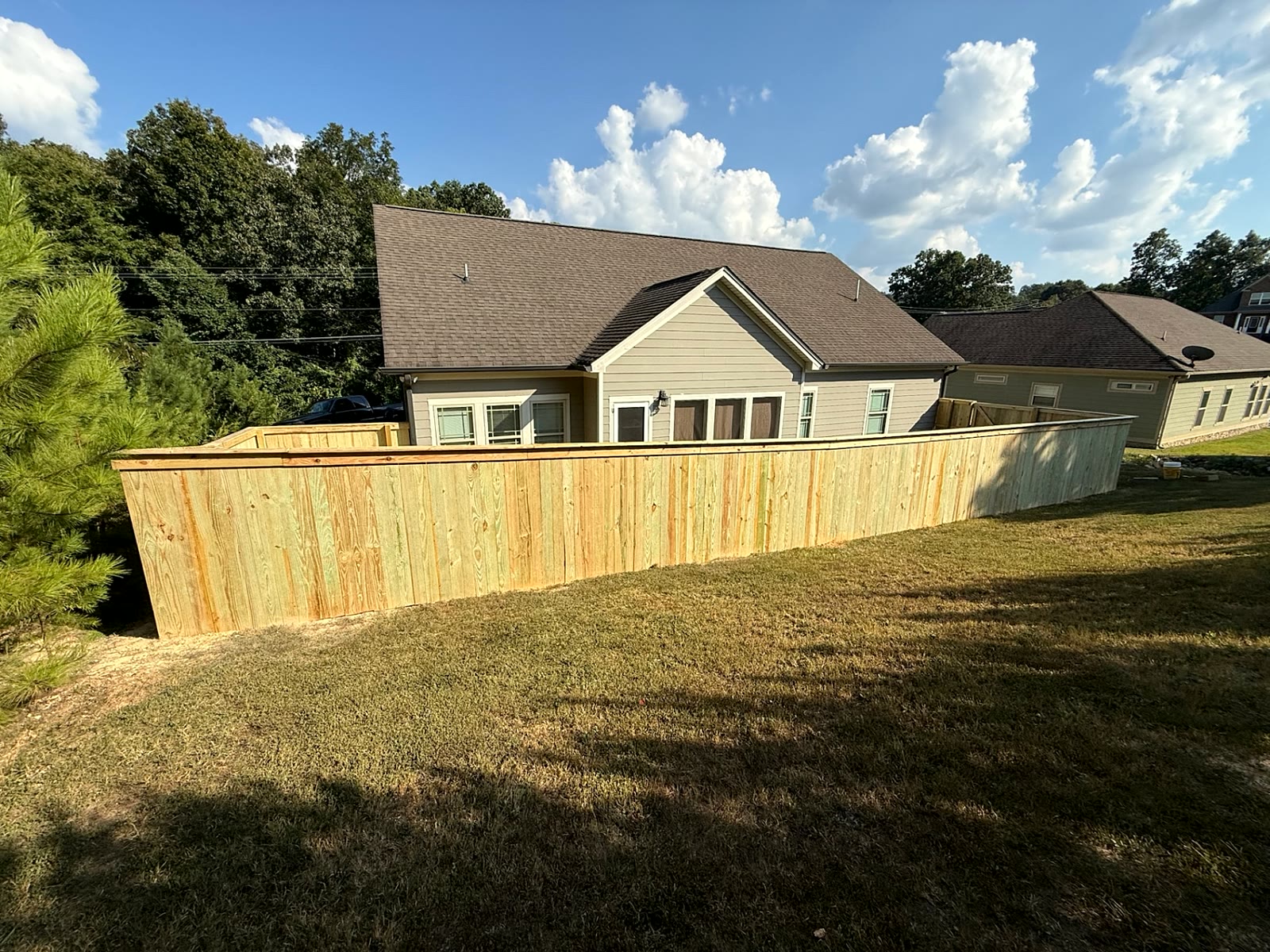 Capped wood privacy fence wrapping a backyard on a sloped lot