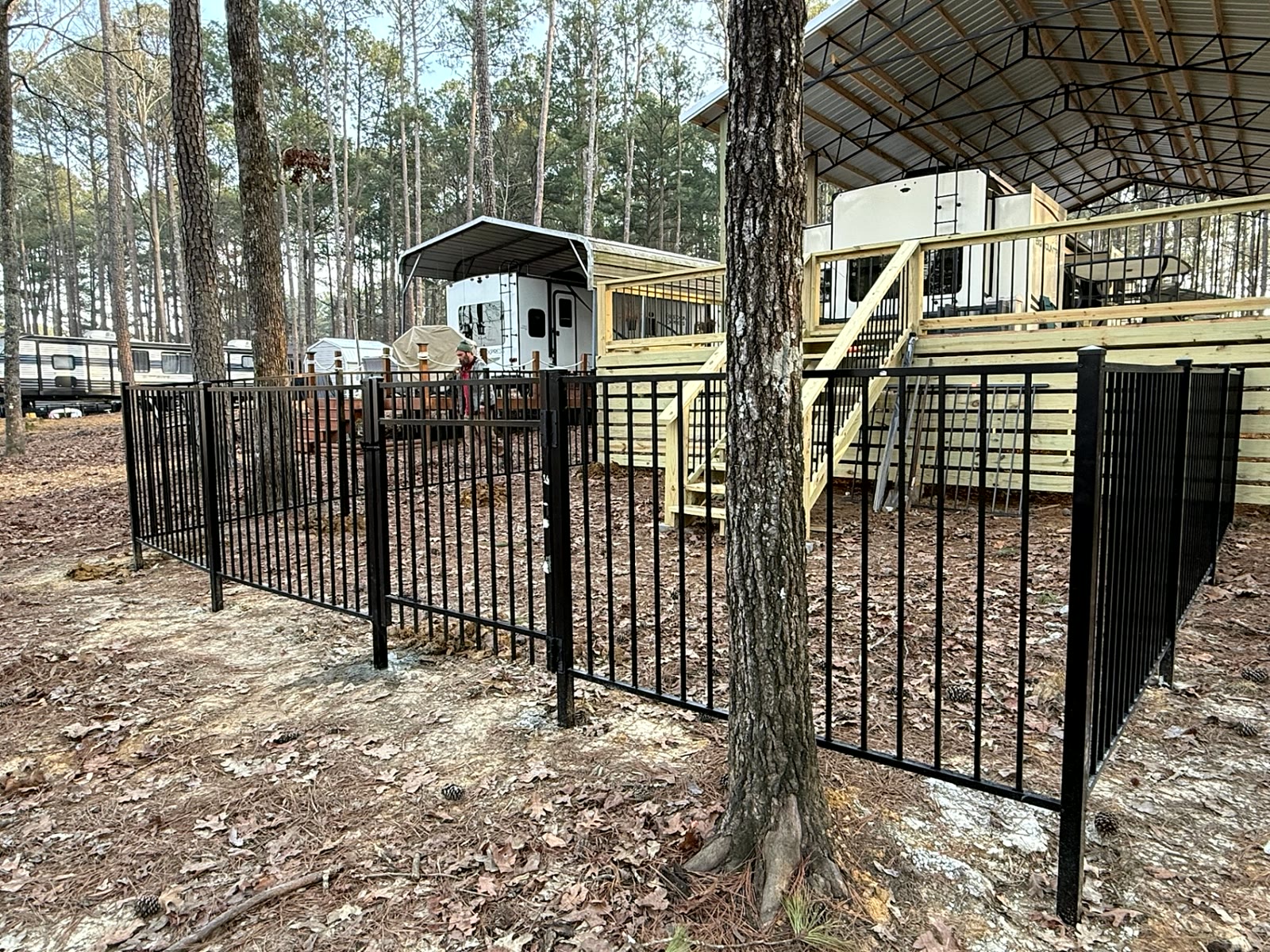 Black aluminum fence and gate around a cabin deck in the pines