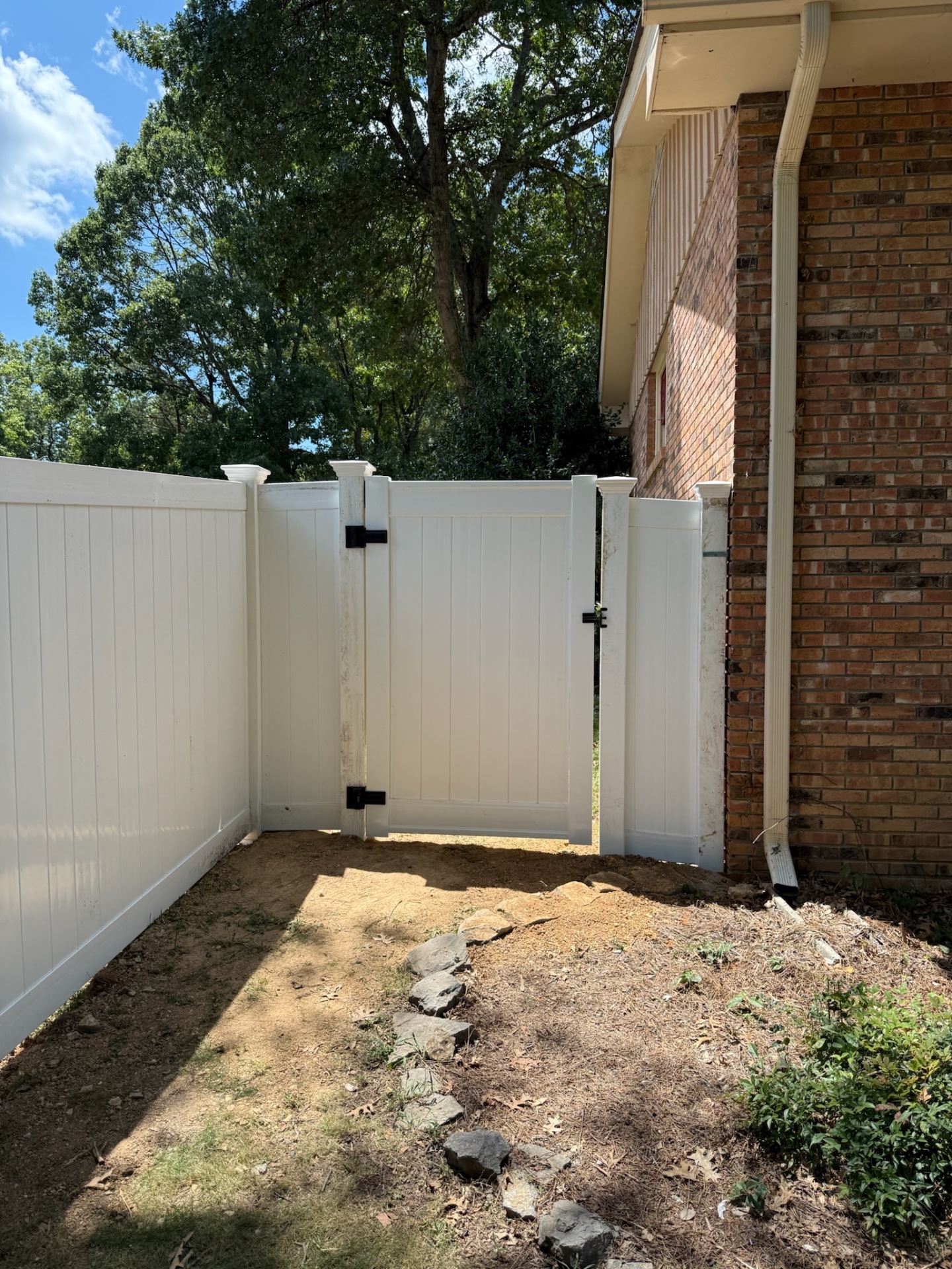 White vinyl walk gate with black hardware beside a brick house
