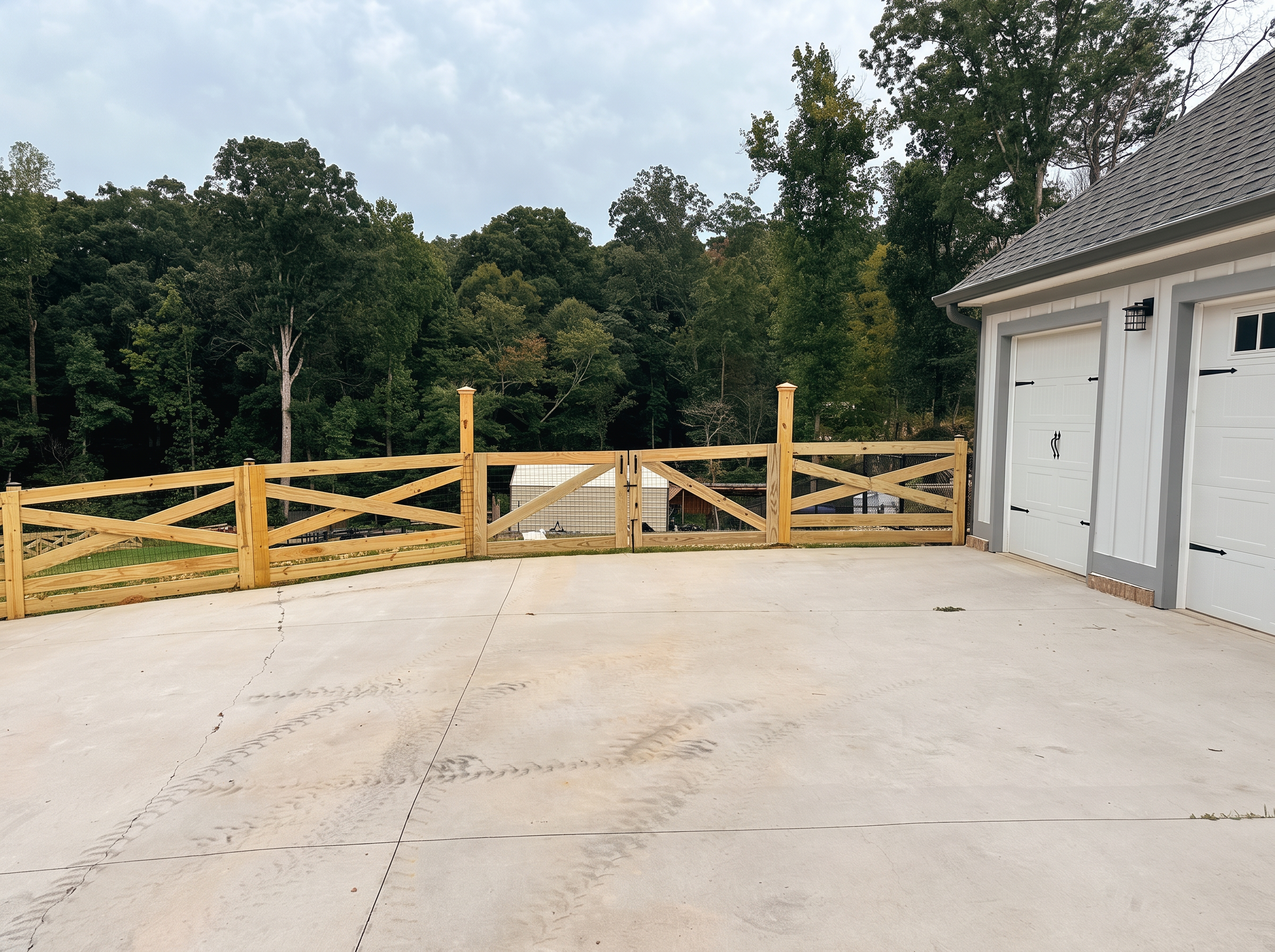 X-brace wood fence and gate along a curved driveway beside a garage
