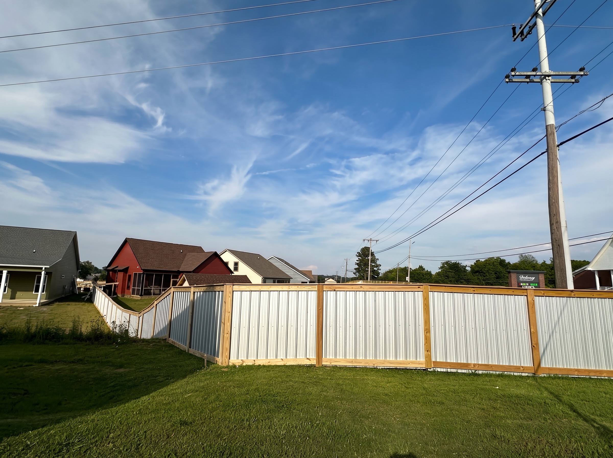 Corrugated aluminum fence with wood framing following a sloped neighborhood property line