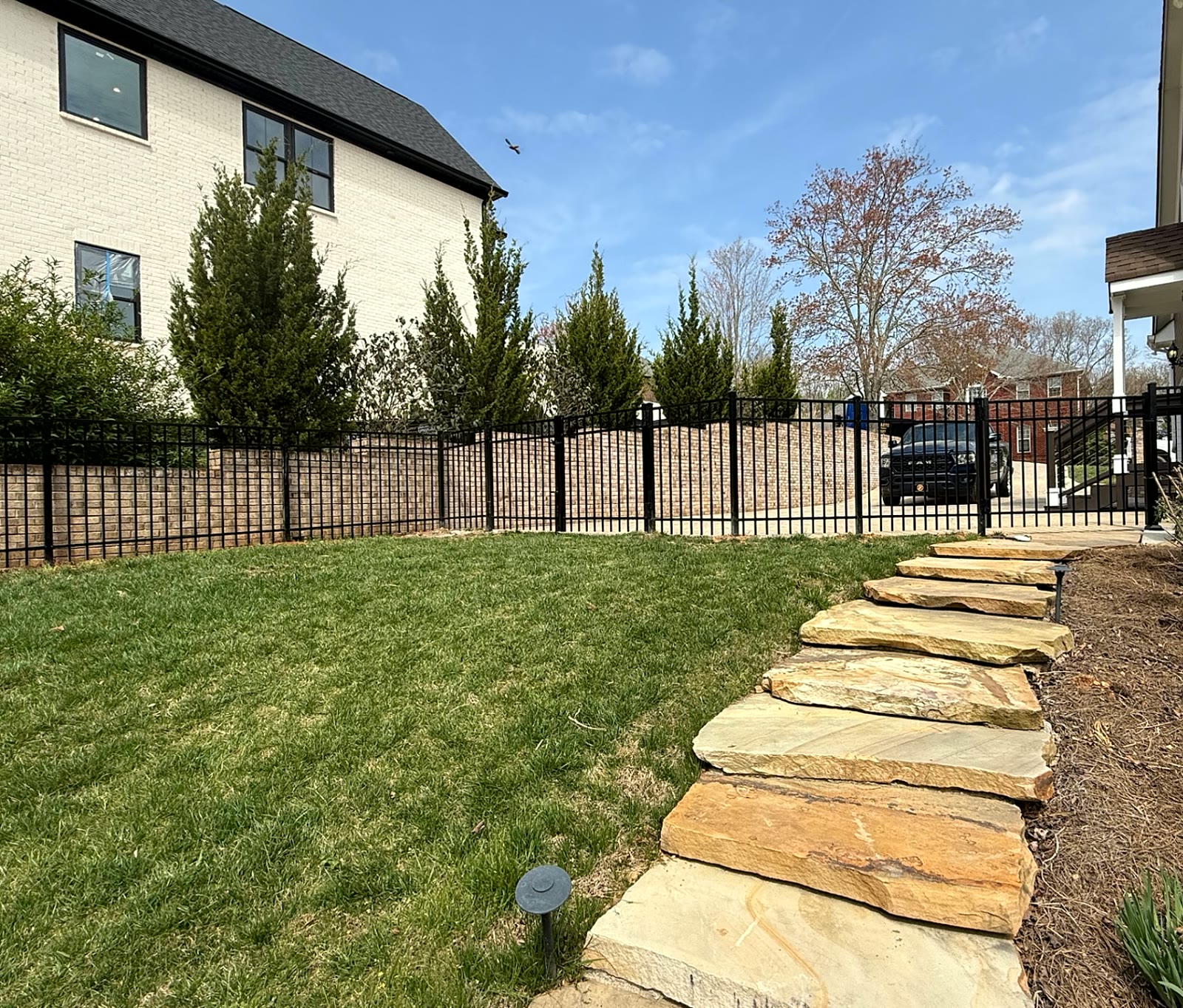 Black aluminum fence and walk gate beside flagstone steps